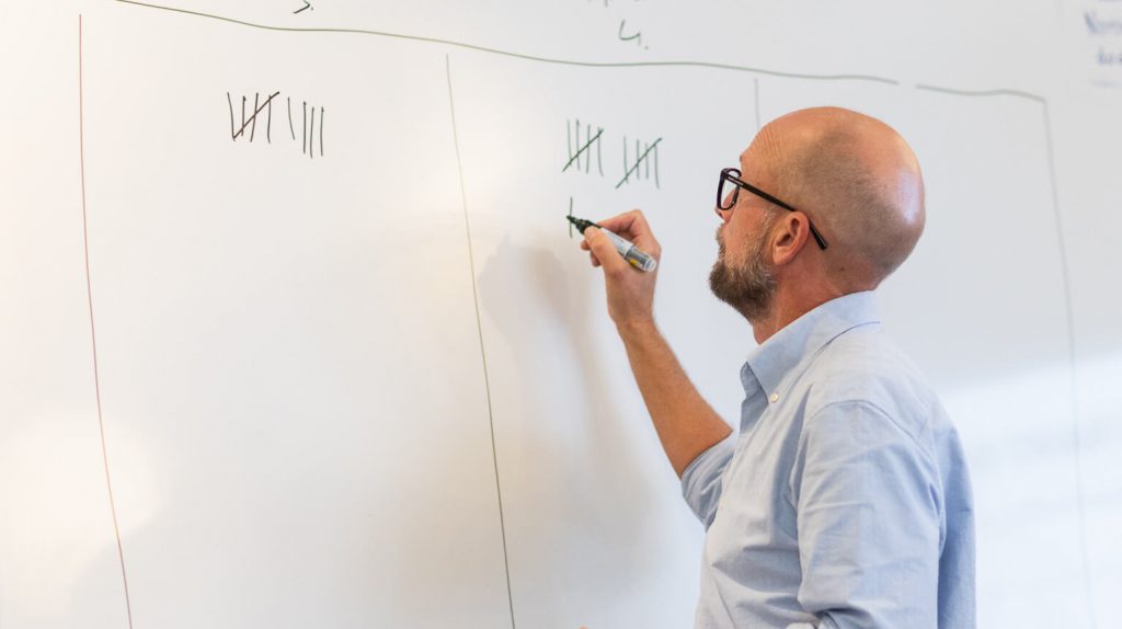 En person antecknar en poängställning på en whiteboard